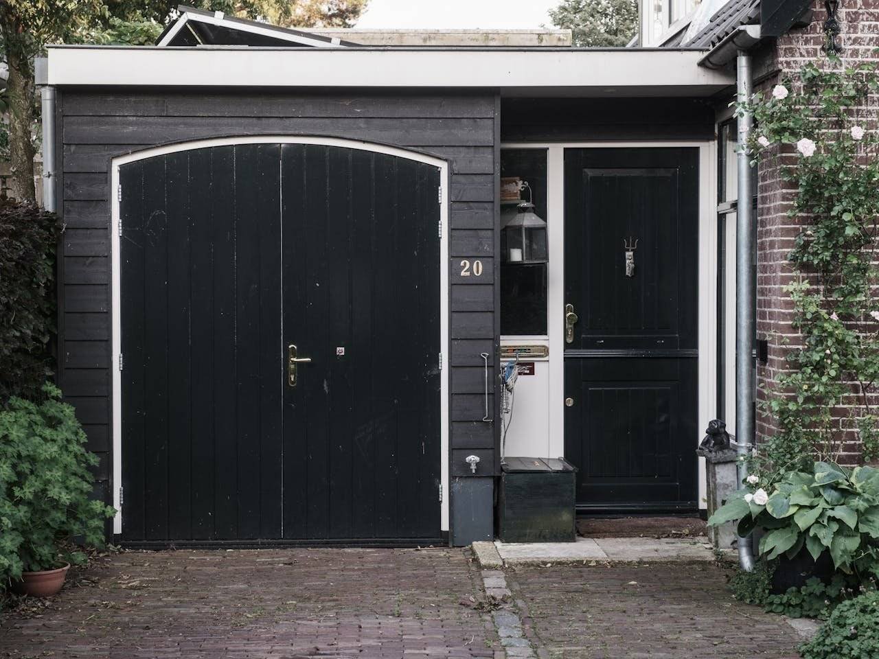 Exterior of a traditional Dutch house with black doors and a landscaped garden.
